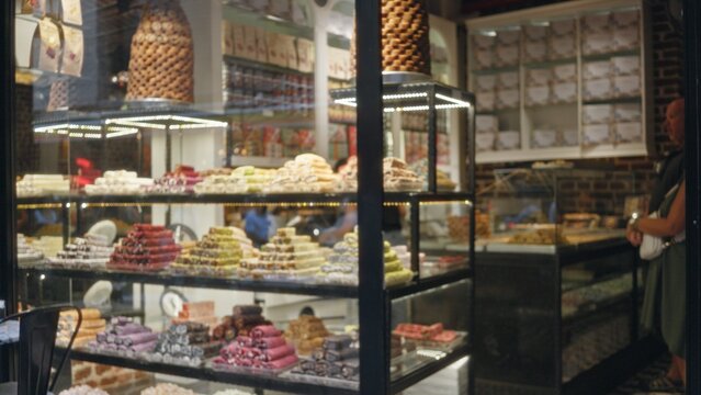 Blurred pastry display with soft bokeh in a shop window case, defocused glass shelves of stacked confections and wrapped boxes; template overlay virtual production.