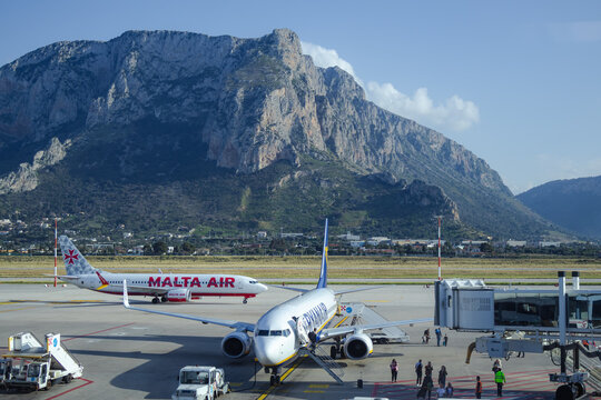 March 07, 2026, Palermo, Sicily, Italy. Multiple aircraft parked at Palermo airport with dramatic mountain backdrop. Aviation sector faces fuel inflation.