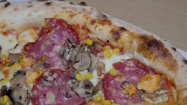 pizza detail with salami cheese vegetables and herbs, close view of baked surface and toppings