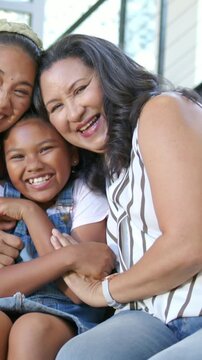 Vertical video: Sharing laughter, family leaning on porch, camera panning right, child in overalls