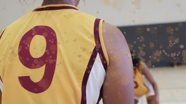 Player 5 entering frame and dribbling basketball to advance offense, animated gold bokeh over court