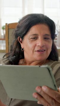 Vertical video: Holding clamshell phone, mature woman checking messages and reading tablet on couch