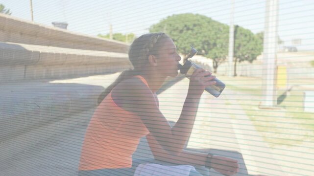 Girl sipping from metal bottle on steps after sports practice, watch showing animated hydration bar