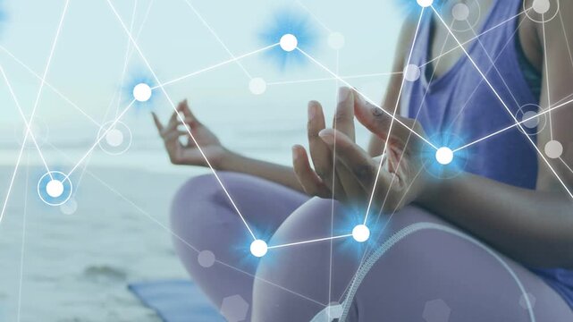 Woman meditating on mat at beach adjusting mudra as glowing nodes growing over hands for wellness