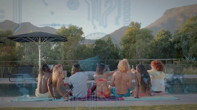 Lifestyle group of seven adults sitting on towel by pool, one lifting drink sparking celebration