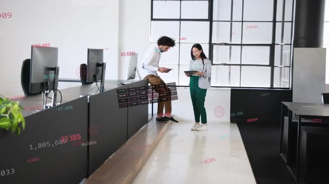 Two coworkers leaning showing tablets walking reviewing business charts with overlays on tablets