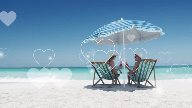 Woman and man clinking bottles on beach, causing floating hearts across umbrella, sea travel ad