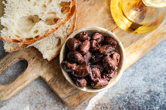Rustic olives, olive oil and sourdough on wooden board