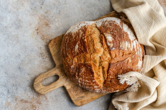 Rustic sourdough loaf on wooden board with linen cloth