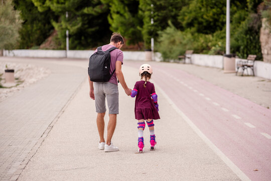 Father teaches daughter roller skating in park