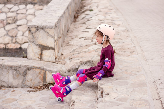 Young girl learns roller skating with safety gear