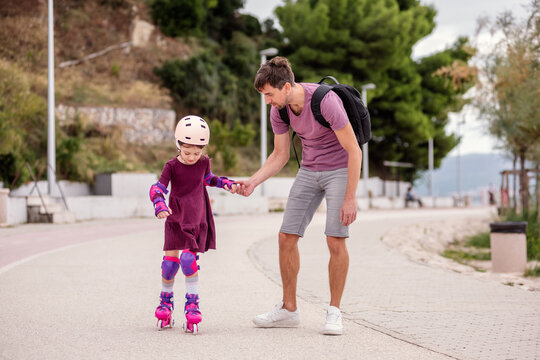 Father teaching daughter roller skating on a sunny day