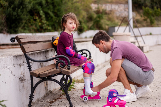 Father assisting daughter with roller skates outdoors