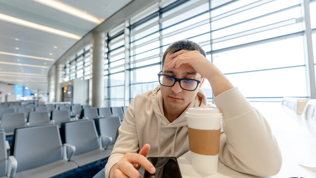 Man waiting at airport with coffee and phone
