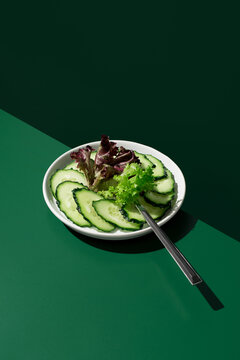 Cucumber and red green lettuce salad on dark background