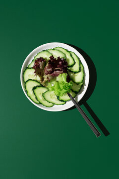 Fresh cucumber and red green lettuce salad on dark green