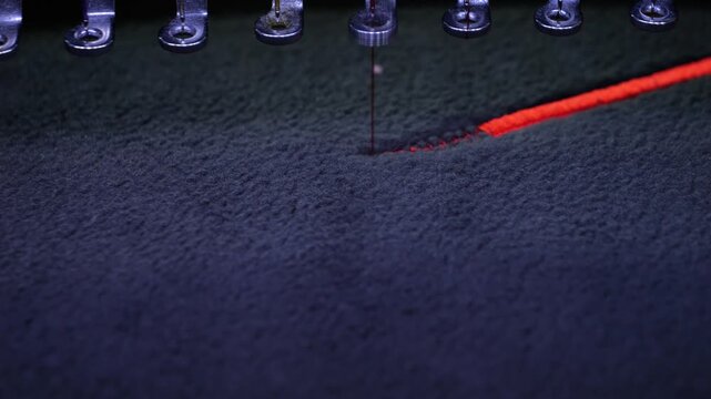 Machine embroidery on a black fleece blouse with red thread. House roof embroidery. Slow motion video. Selective focus close-up.