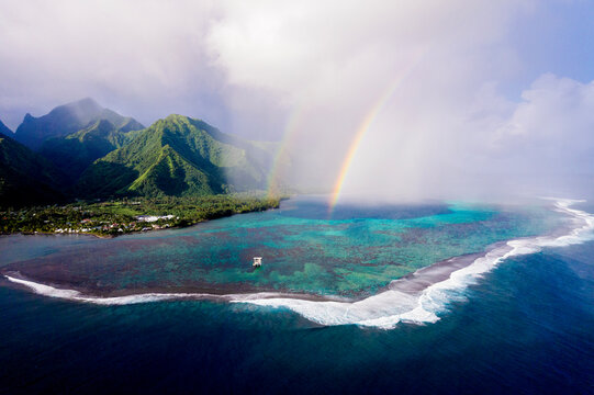 Aerial lagoon rainbow over lush island in French Polynesia