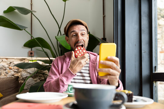 Man enjoying coffee time and snack while taking a selfie