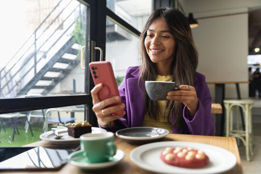 Woman enjoying coffee time while texting in a modern cafe