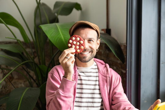 Smiling man with cookie at cafe during coffee time break