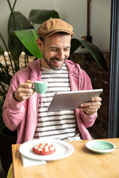 Smiling man using tablet during coffee time at cafe table