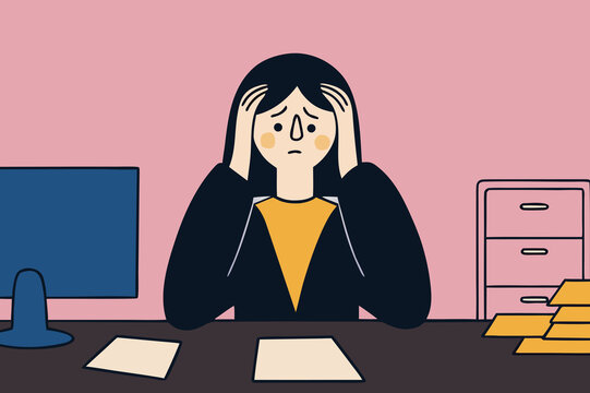 Stressed woman at office desk with paperwork and computer