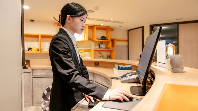 Taiwanese hotel receptionist working at modern front desk