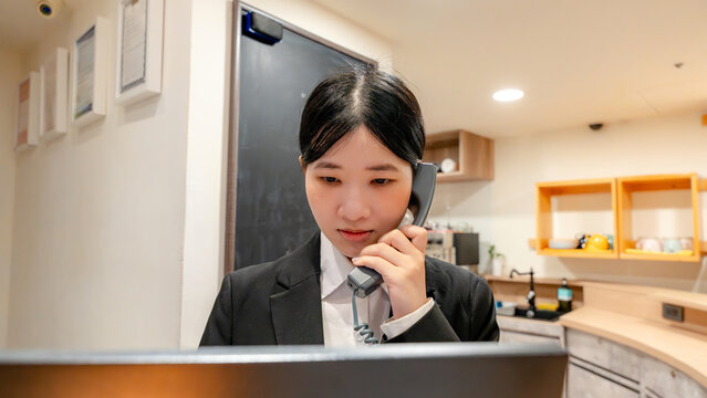 Taiwanese hotel receptionist answering phone at front desk