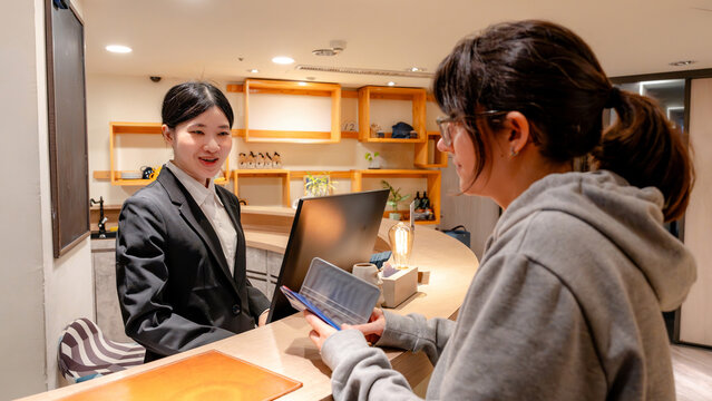 Taiwanese hotel receptionist assisting guest at front desk