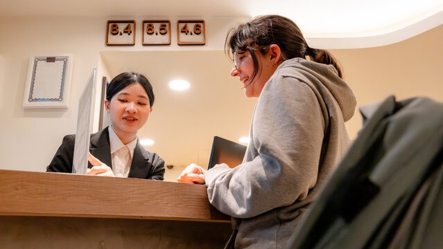 Taiwanese hotel receptionist assisting guest at front desk