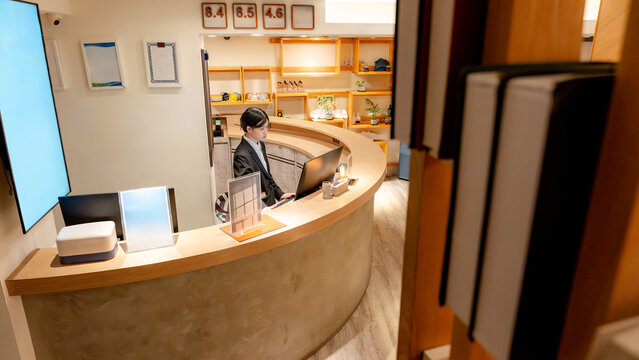 Taiwanese hotel receptionist working at modern front desk