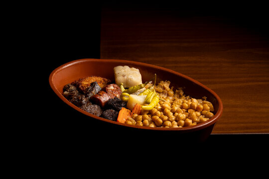 Traditional Spanish cocido with chickpeas in a clay dish