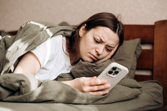 Relaxing day off in bed with smartphone and cozy blanket