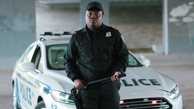 A dedicated officer stands guard next to their patrol car, ensuring community safety