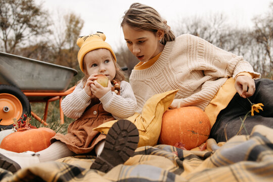Sisters sitting with pumpkins on blanket in autumn