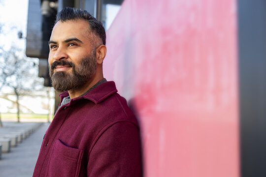 Arab man leaning on city wall in casual winter coat