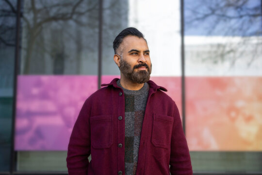 Arab man standing outdoors by modern glass building facade