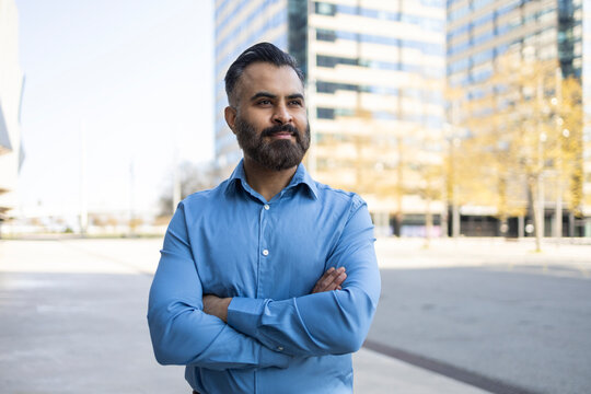 Arab businessman standing outdoors by modern office buildings