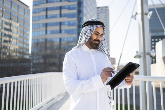 Arab sheikh businessman using tablet in modern city setting