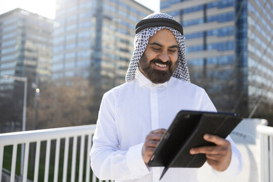 Arab businessman sheikh using tablet outside modern office