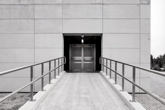 Entr&eacute;e de b&acirc;timent moderne avec rampe d&rsquo;acc&egrave;s PMR et architecture minimaliste contemporaine