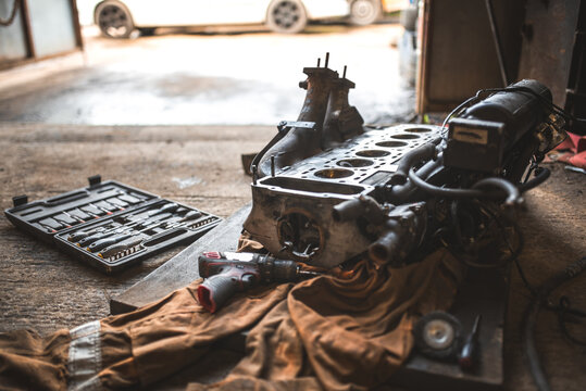 Car engine block and tools laid out in a workshop for repair or maintenance