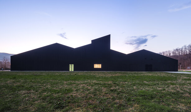 Modern black candy factory building at dusk in rural field