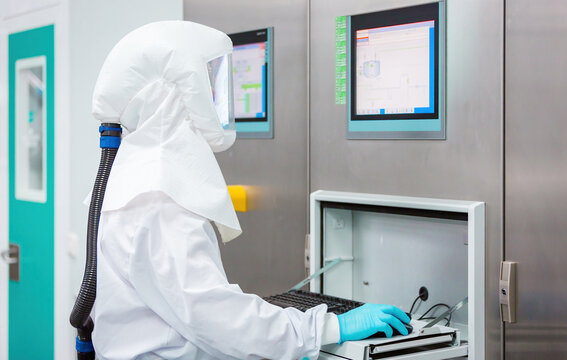 Technician in protective suit monitoring candy lab equipment