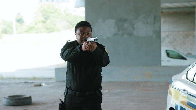 Young african american policeman with pistol arrest offender in mask stand hands up in patrol car in handcuffs burglar crime hold danger gangster gun robber illegal law bad guy close up slow motion