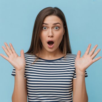 Surprised young woman with shocked expression on blue background reaction portrait