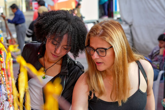 Young women browsing an outdoor market stall together