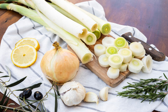 Fresh leeks sliced on wooden board with herbs and lemon