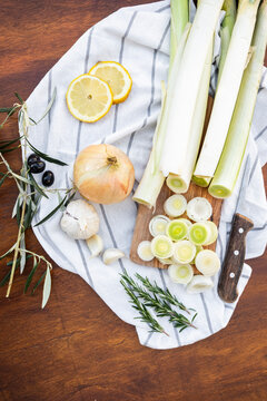 Fresh leeks and herbs on rustic board with lemon slices